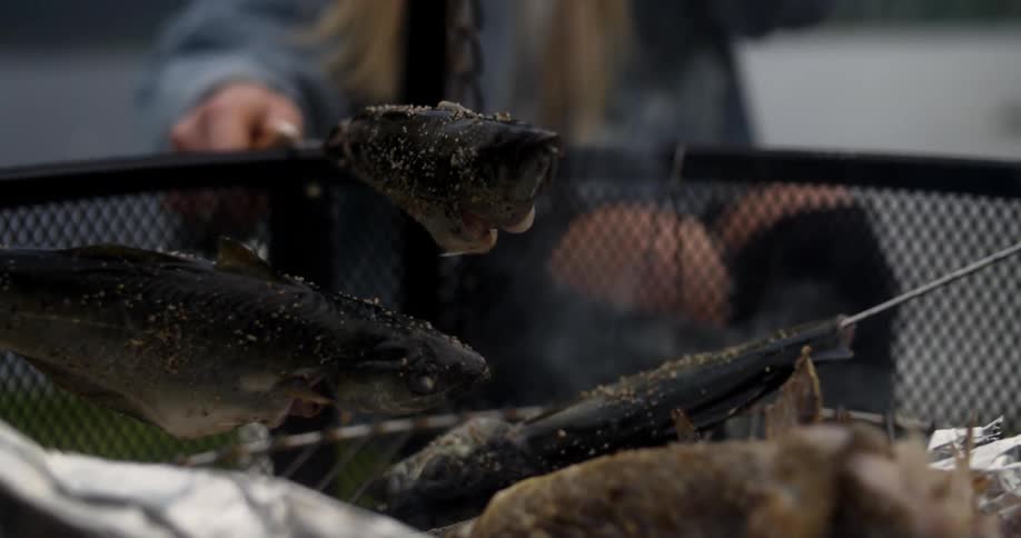 Fish is cooked over a smoking grill