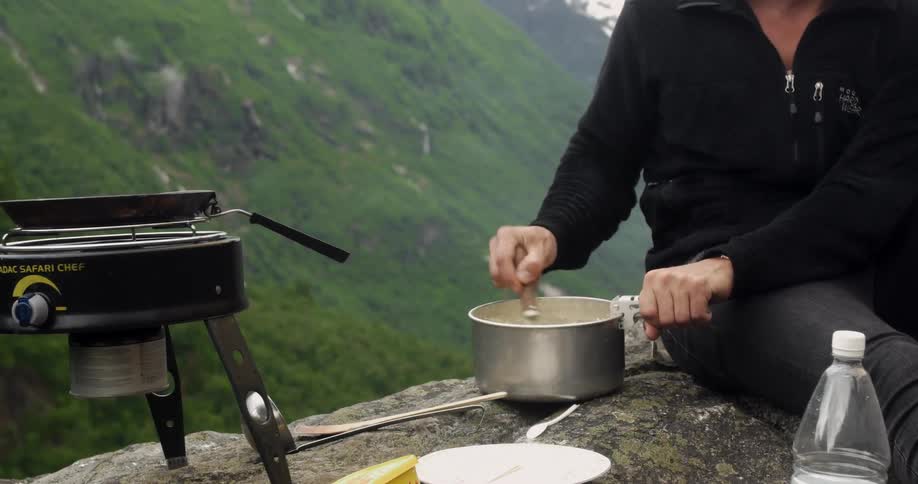 A person mixes in a pot at a campsite