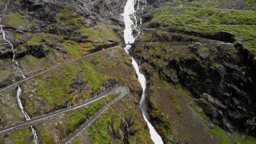A rising aerial view of a river cutting down the side of a mountain