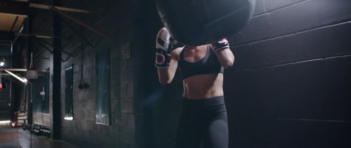 Woman punches a bag with boxing gloves on