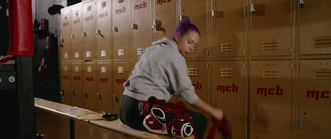 A woman wraps her wrist with athletic tape in a locker room