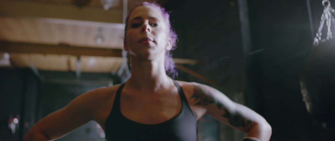 A woman is posing in the gym wearing boxing gloves