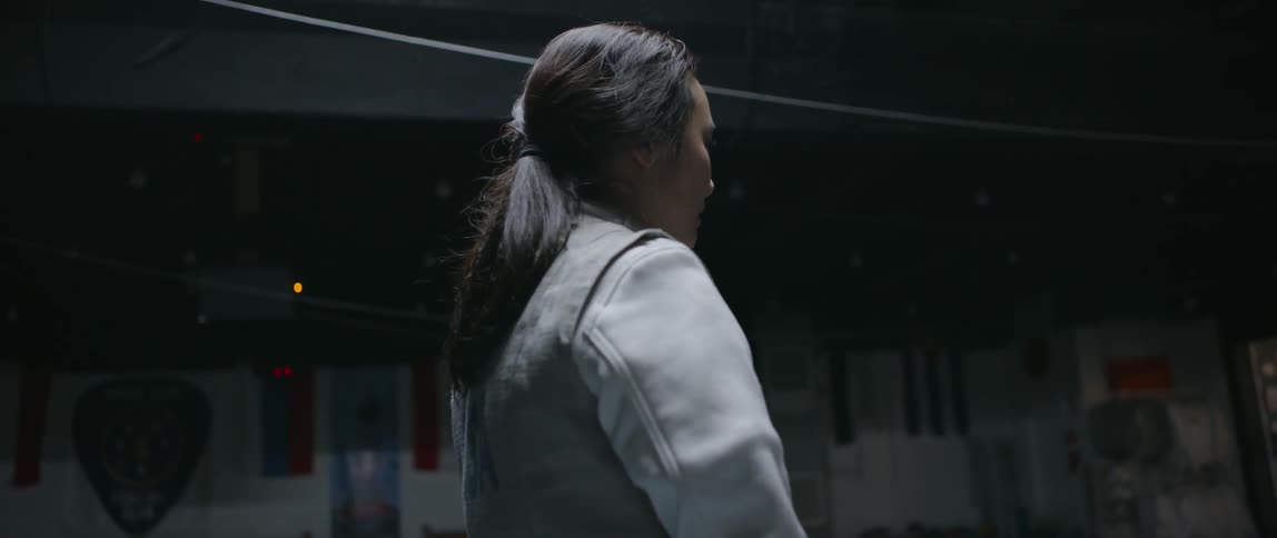 Woman in fencing gear walking around a gym