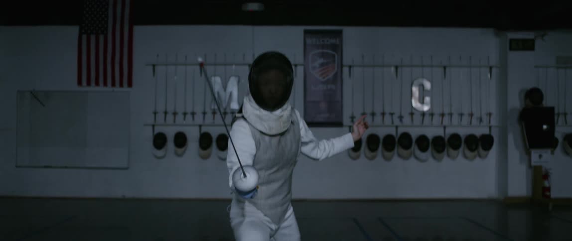 Person practices fencing in an indoor arena