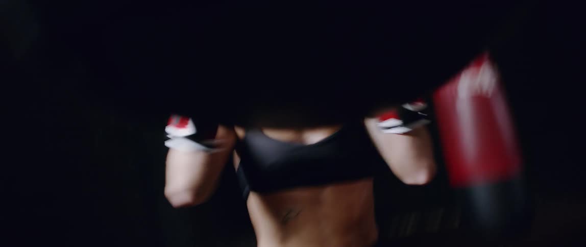 Woman hits punching bag in gym