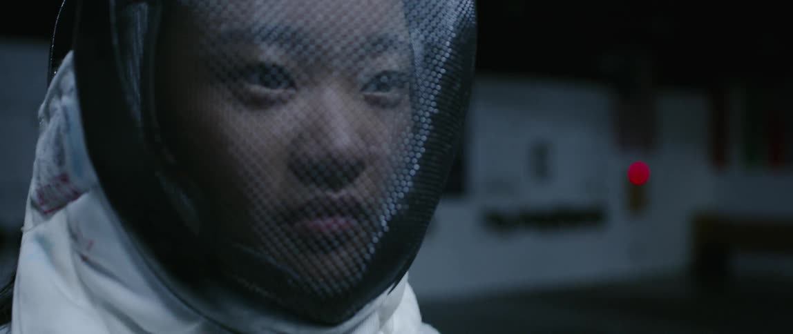 A girl is wearing a fencing mask