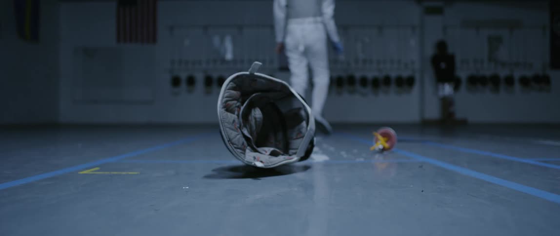 Person in fencing gym drops helmet and sword