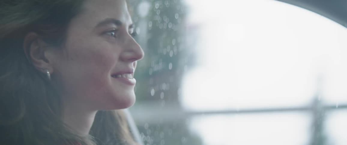 A woman smiles and talks as she drives