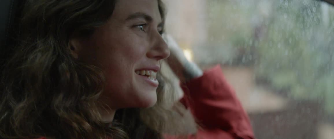 The woman smiles and talks as she drives