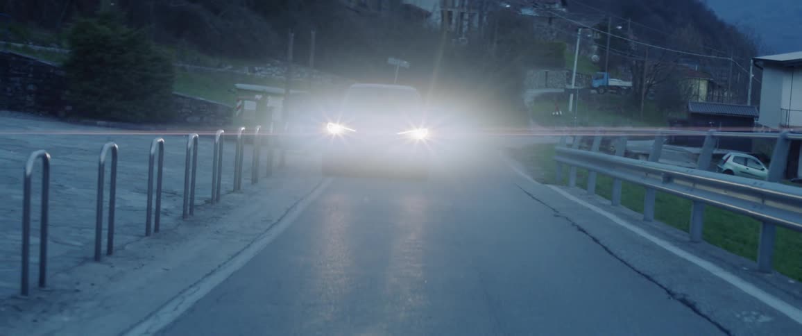 The car is driving on the small road at sunset