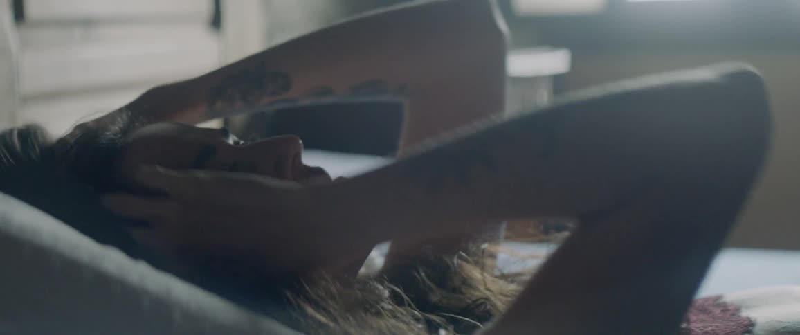 A woman is lying in bed in daylight moving her hands