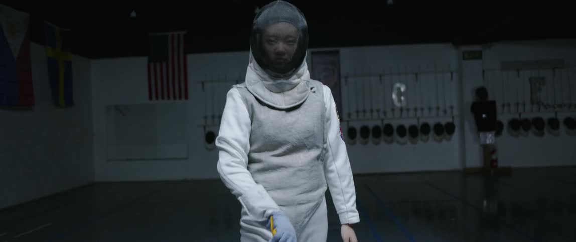 Asian woman wearing a uniform stands in a dim room