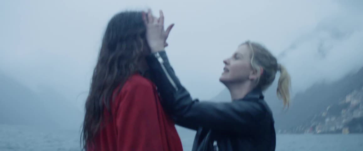 Two women standing near a lake on a foggy day