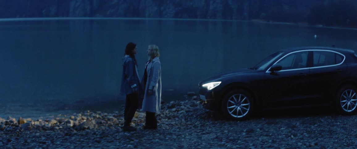 Two people approach each other by the lake