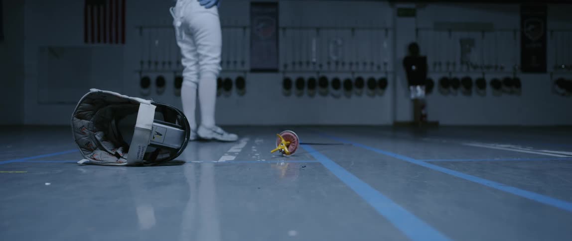A fencer drops their helmet and sword