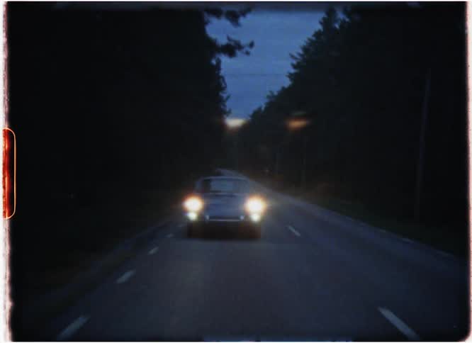 Headlights shine from a car driving down the road at night