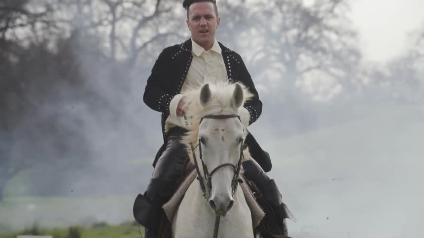 Man rides a white horse through the mist