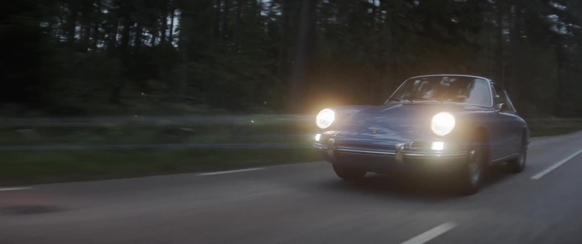 A small sports car travels with headlights on