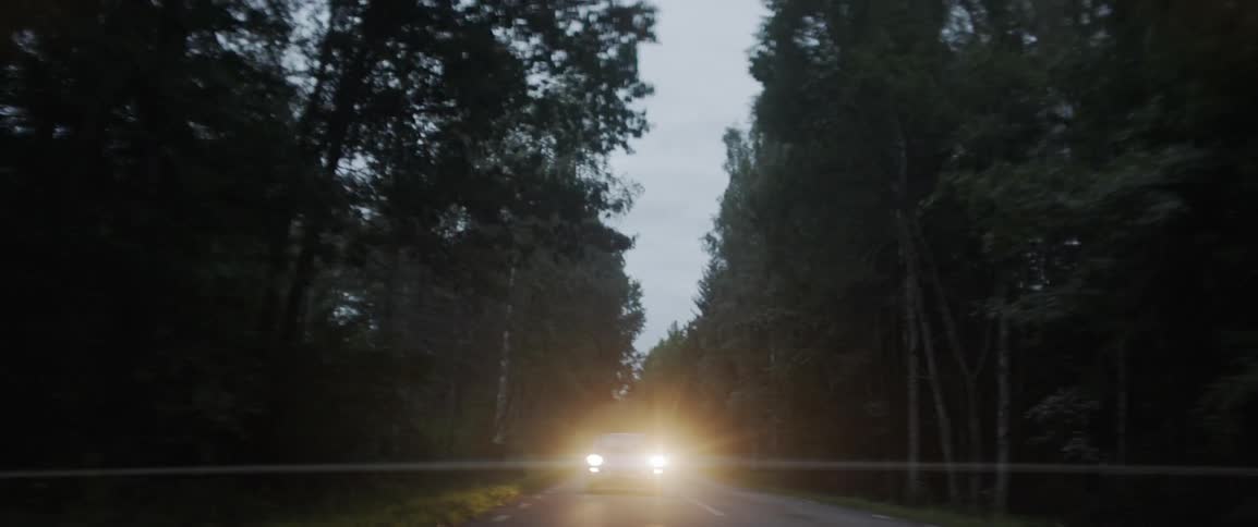 Headlights of a car shine as a car travels down a street