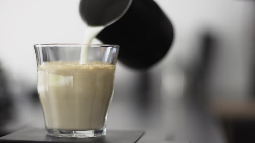 Milk is poured from a pitcher into a glass