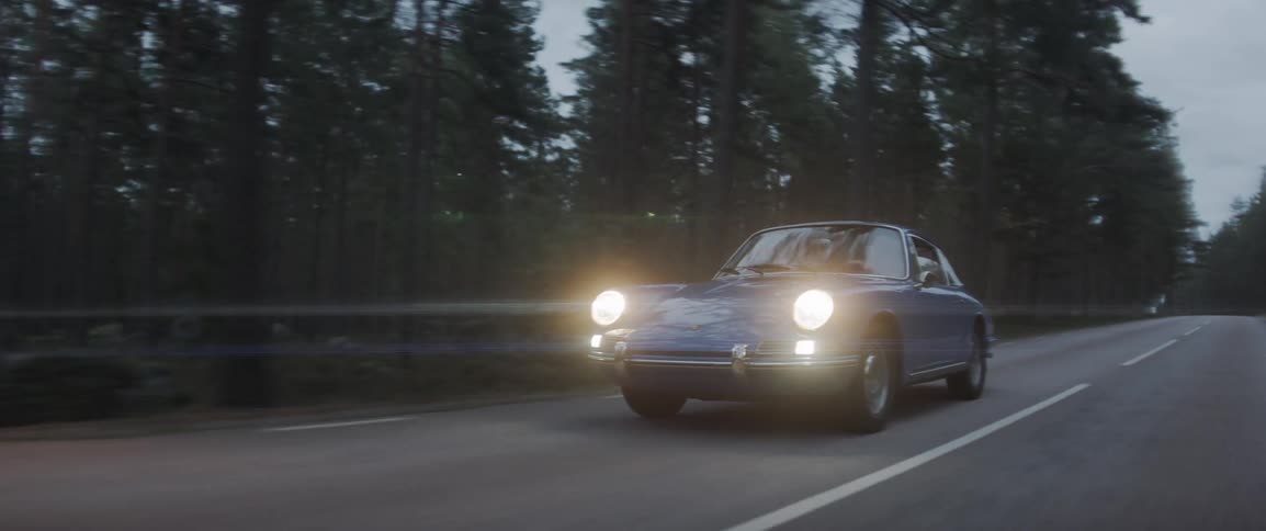 An antique car drives on a forest road