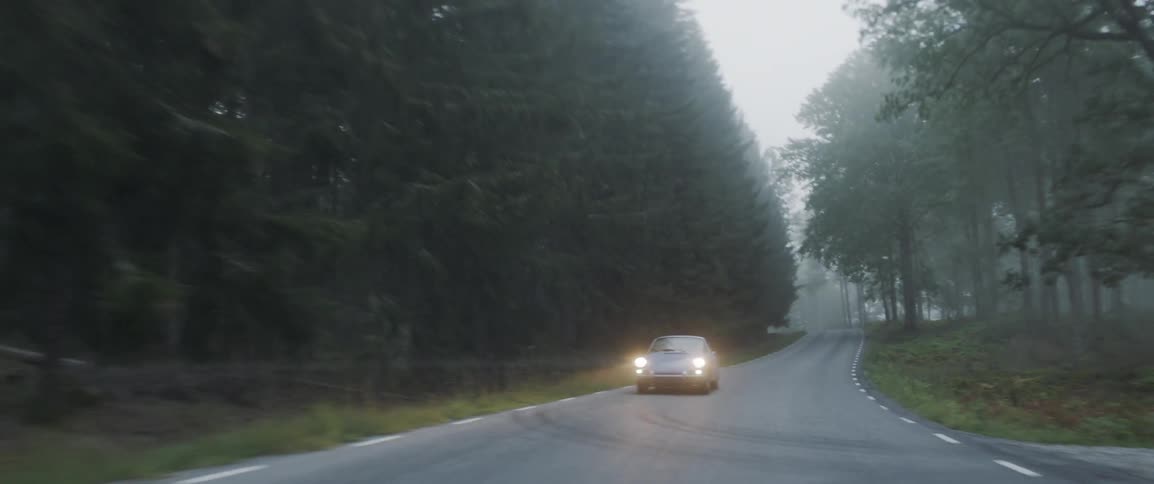 The vehicle is driving down the road by the forest