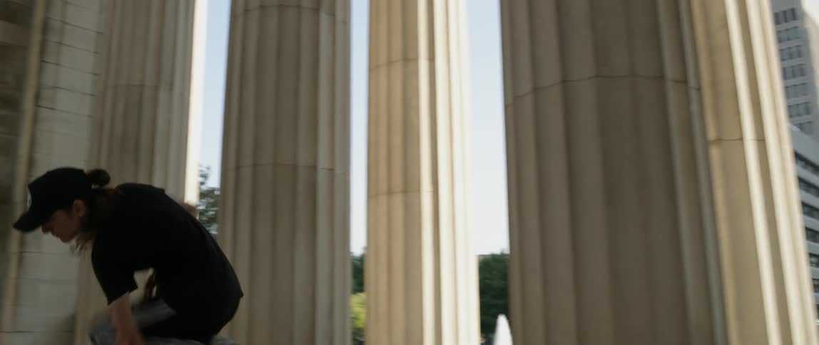 Person dances near pillars of a large building