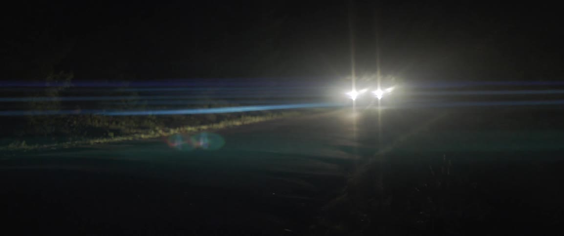 The car drives down the road at night