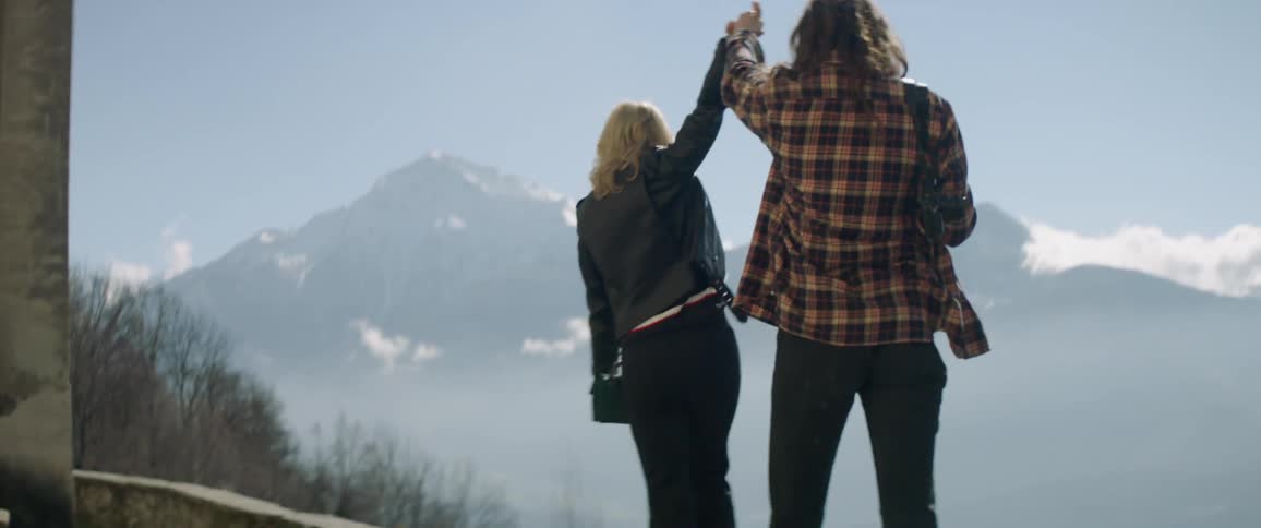 Two people walk together holding hands on a cliff wall