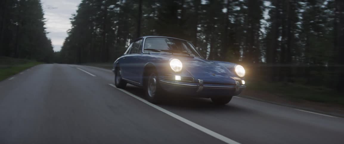 An antique car drives on a forest road