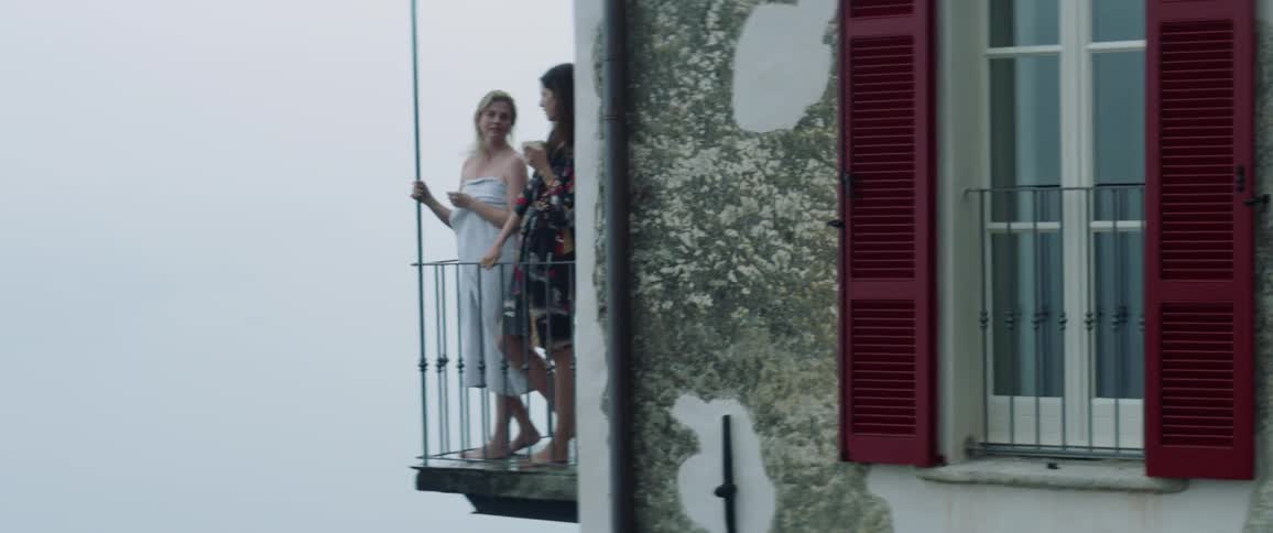 Woman stands on a balcony sipping out of a mug