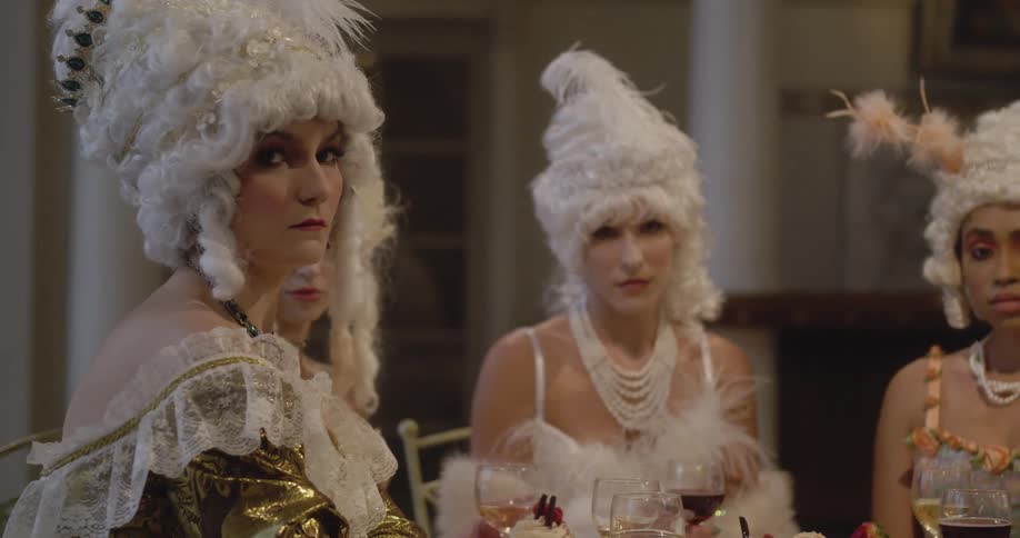 A group of women in old fashioned garb sit at a table