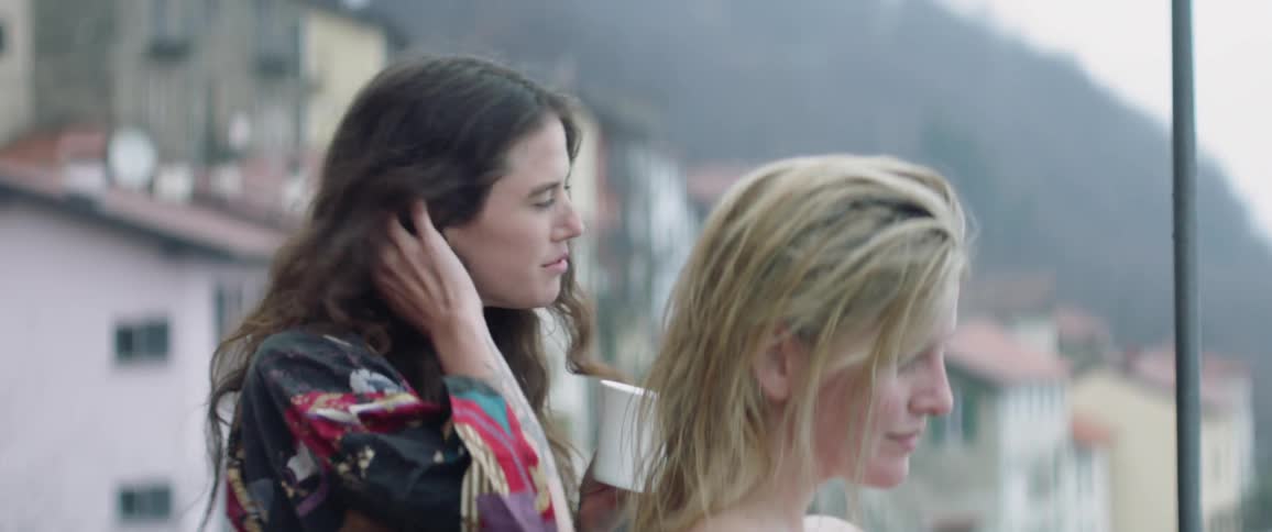 Two women drink and look out over the city