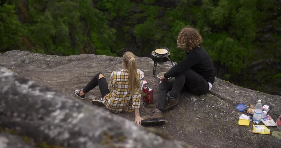 A man and woman cook in the wilderness