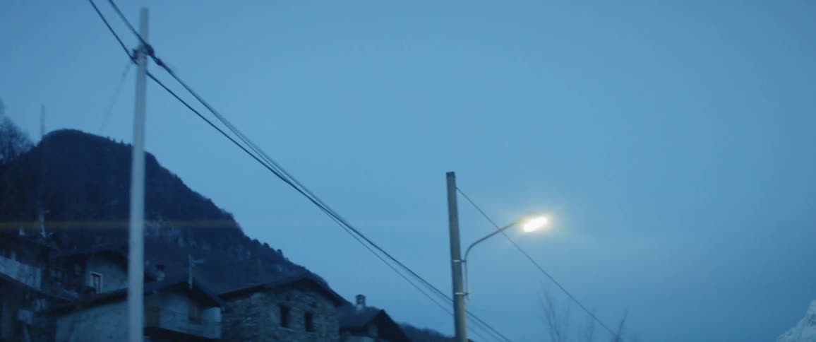 A car drives beneath a glowing street lamp