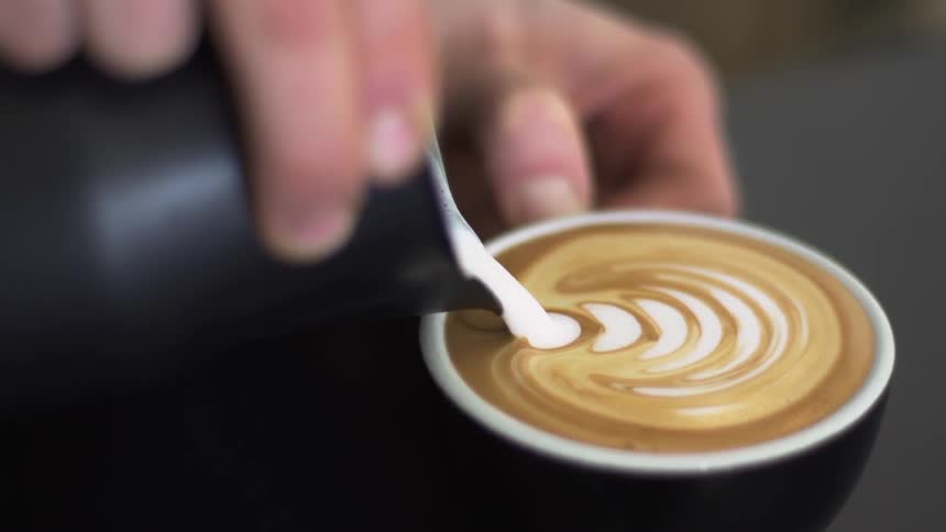 Milk foam is poured into a coffee creating a Latte Art
