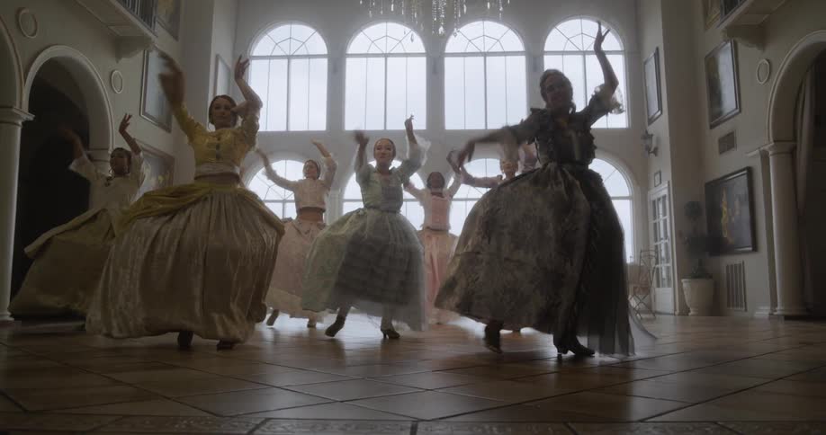 Women in old fashioned dresses dance in unison