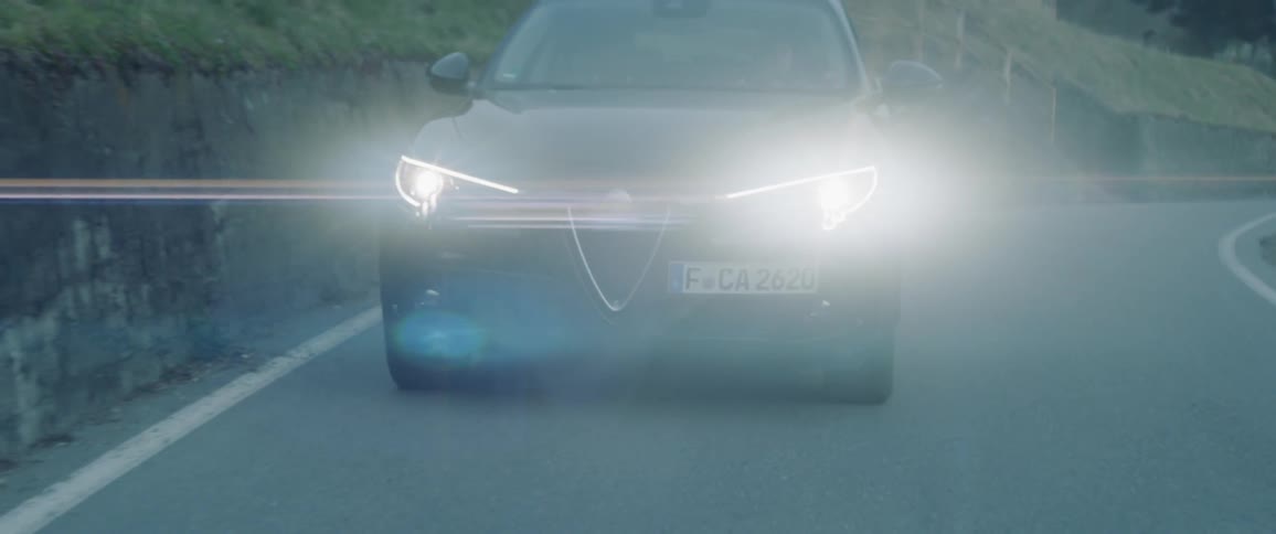 The car rides on the road with headlights on