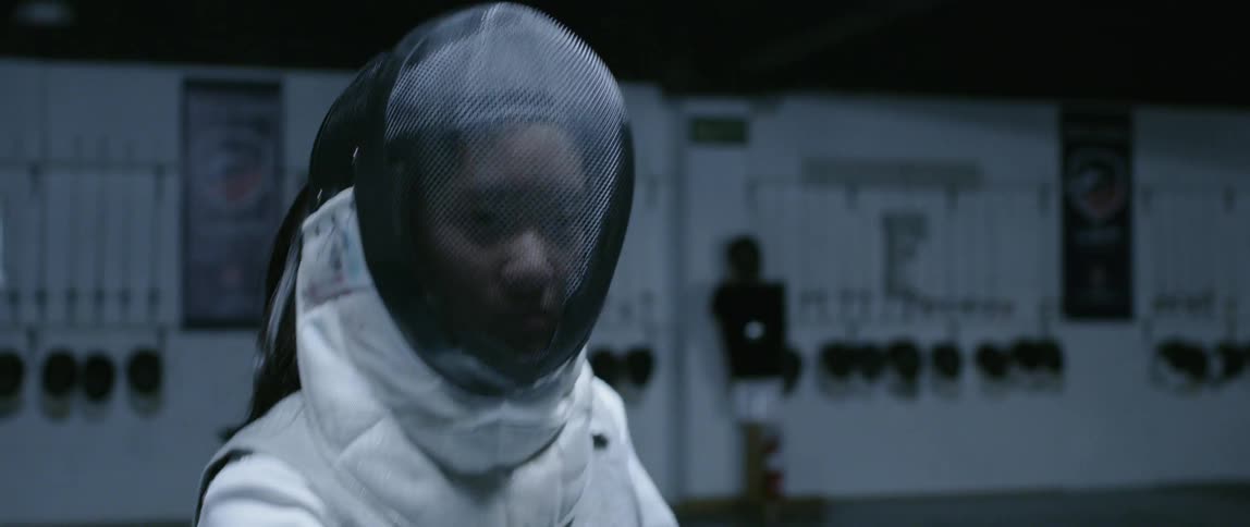 A fencer closes her helmet and moves back