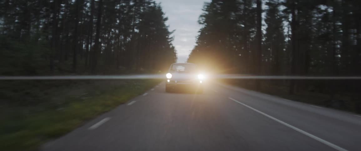 An old sports car drives on the rural road at night