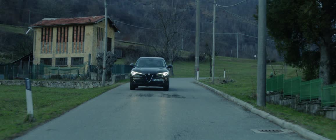 A car with headlights on travels on a rural road