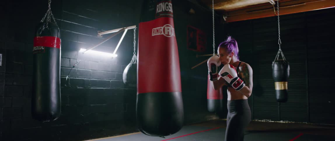 Woman punches a bag with boxing gloves on