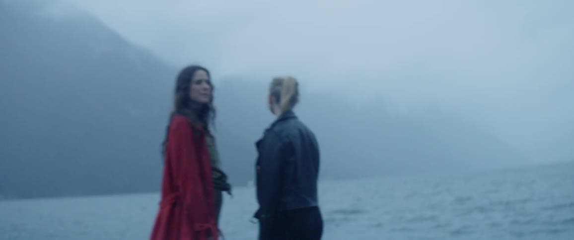 Laughing couple standing by the lake shore in the rain