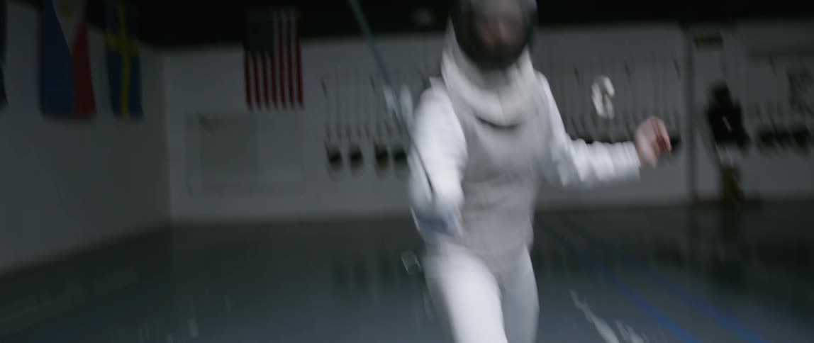 Person practices fencing in an indoor arena