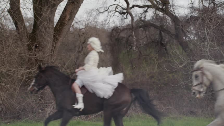 People in victorian era clothes ride horses