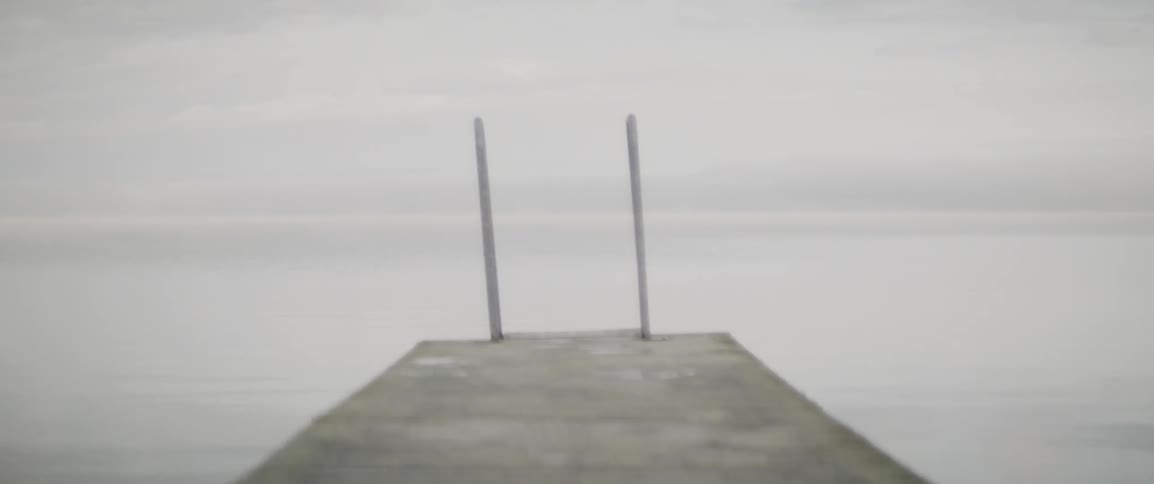 Dock with two posts at the end of it in a large body of water