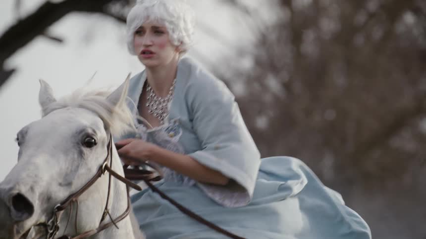 A woman is riding a white horse in a dress