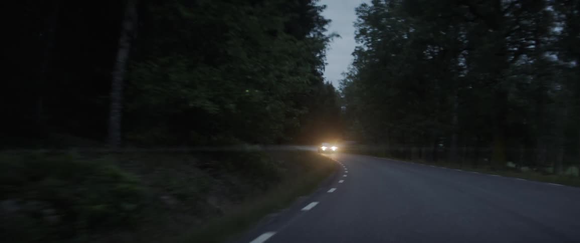 The car is making a turn on the dark road