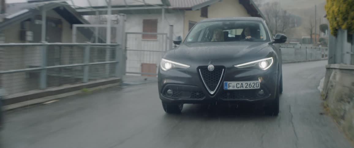 A car travels on a rural road in the rain