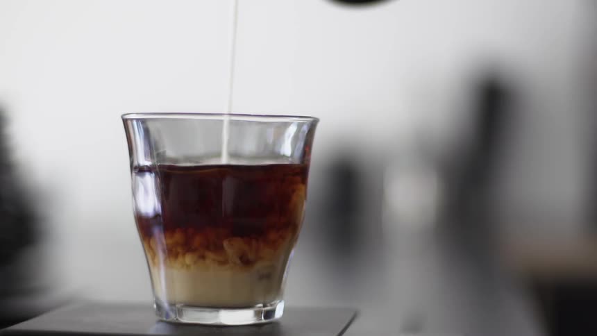 Milk is poured into a small coffee glass